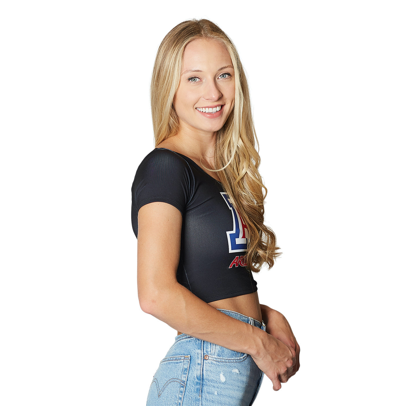 Woman wearing a black crop top with a logo and blue jeans on a white background