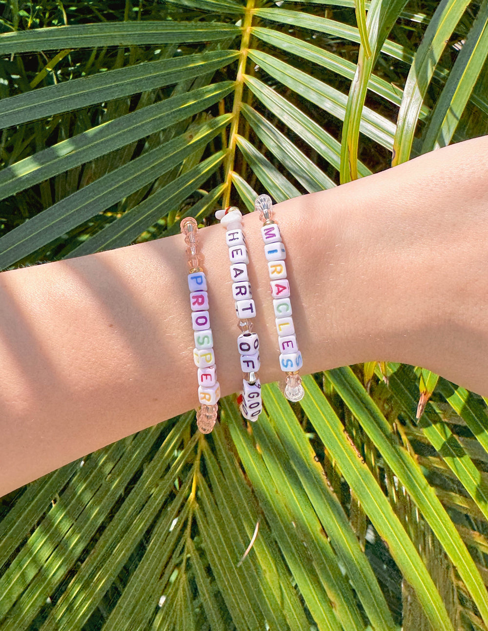 Pink beaded bracelet with colorful letter beads on a white background