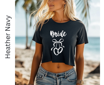 Woman wearing a black 'Bride' t-shirt with a bow graphic on a beach.