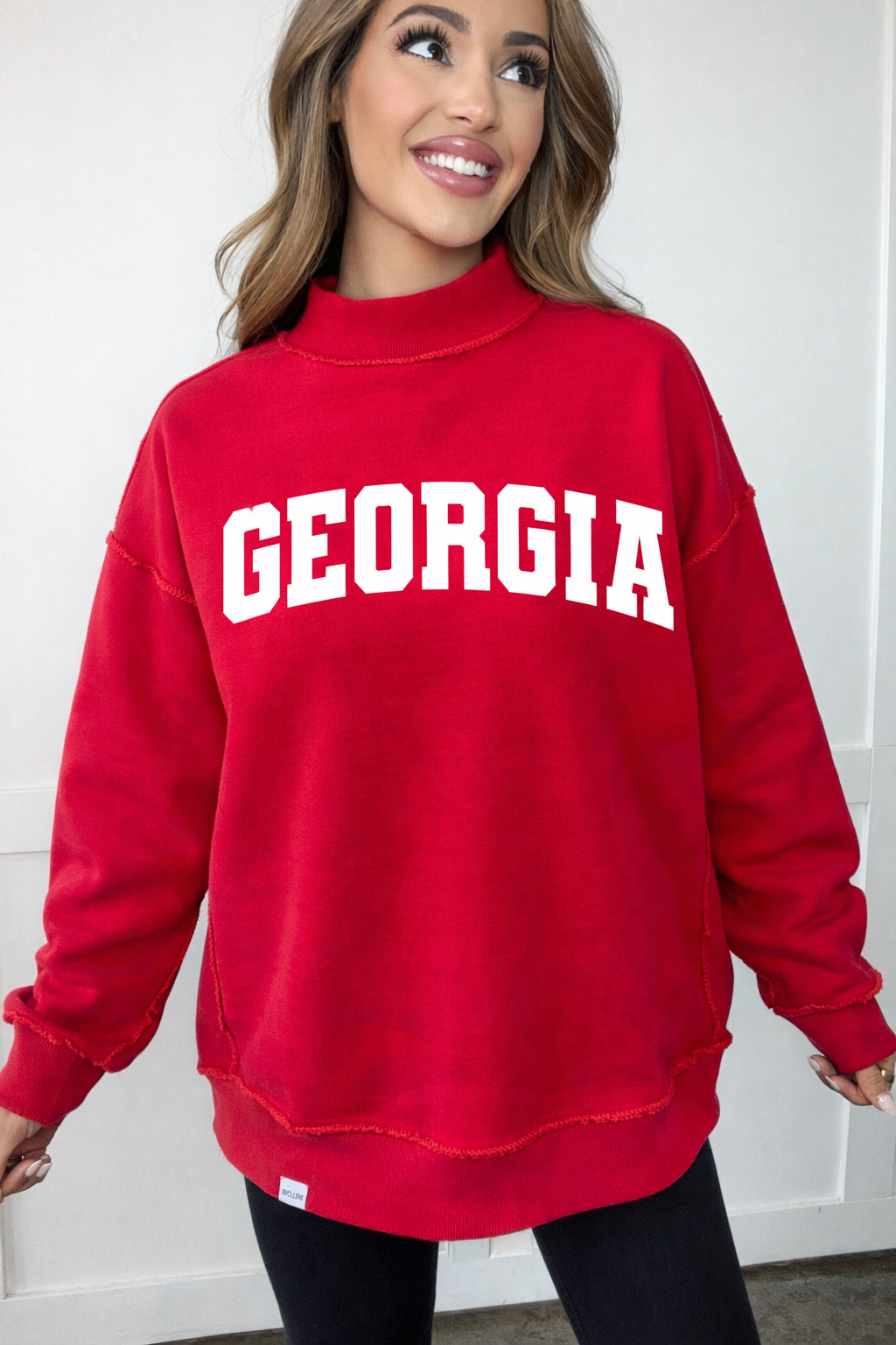 Person wearing a red 'Georgia' sweatshirt against a white background