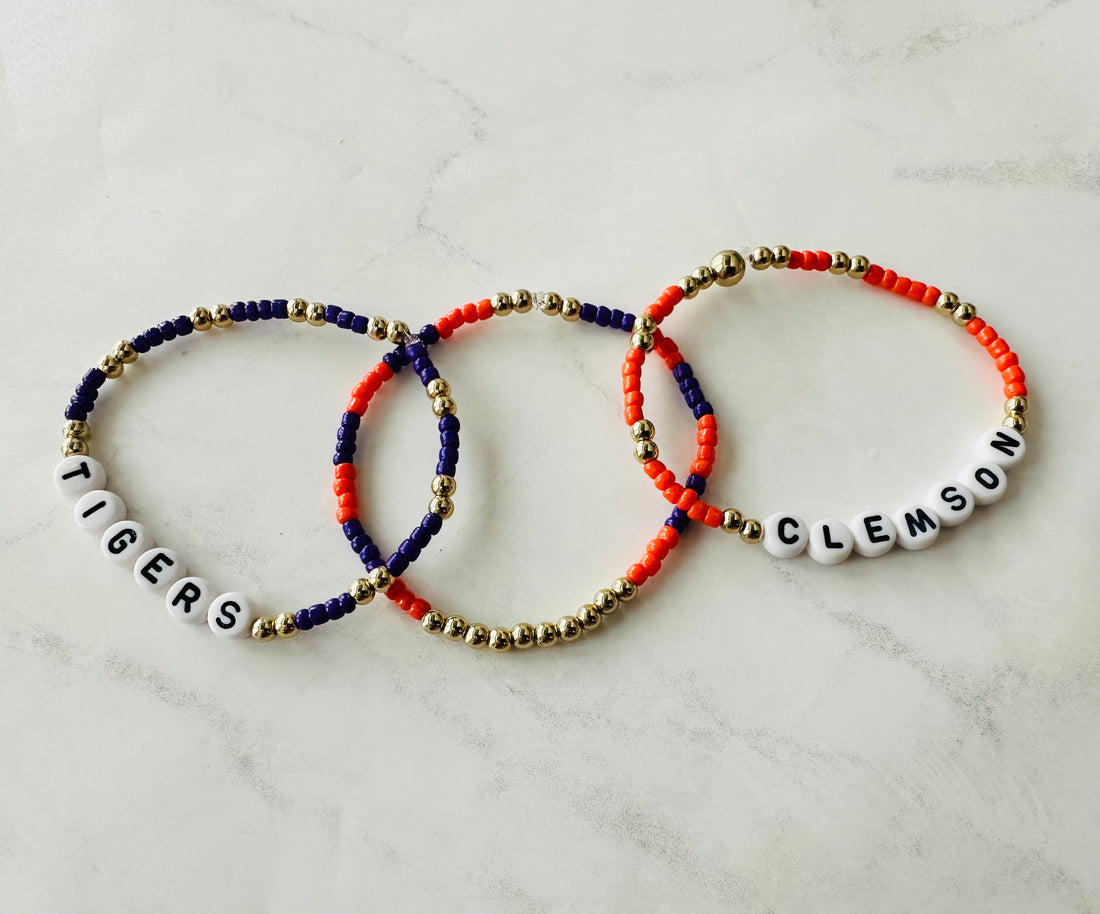 Three beaded bracelets with 'Tigers' and 'Clemson' text on a marble surface