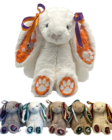 White Clemson University Jellycat bunny with orange and purple ribbons and paw prints, surrounded by smaller plush bunnies with colorful ribbons.