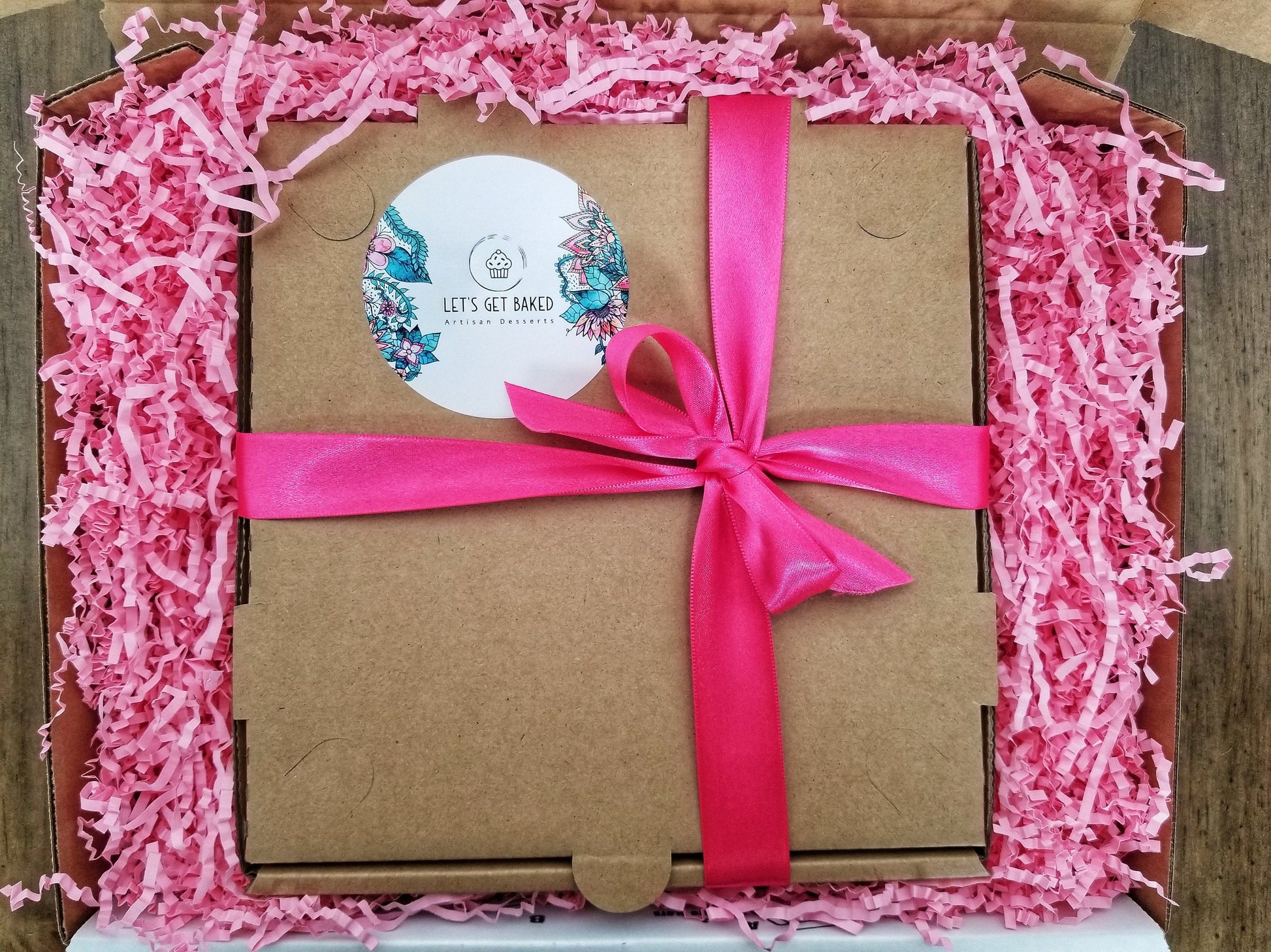 Gift box with a pink ribbon and decorative paper on a wooden surface