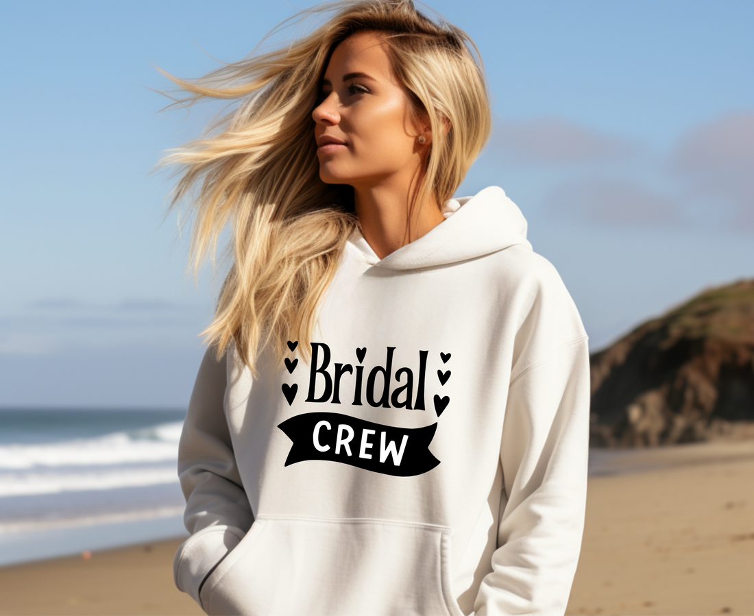 Woman wearing a white hoodie with 'Bridal Crew' text on a beach