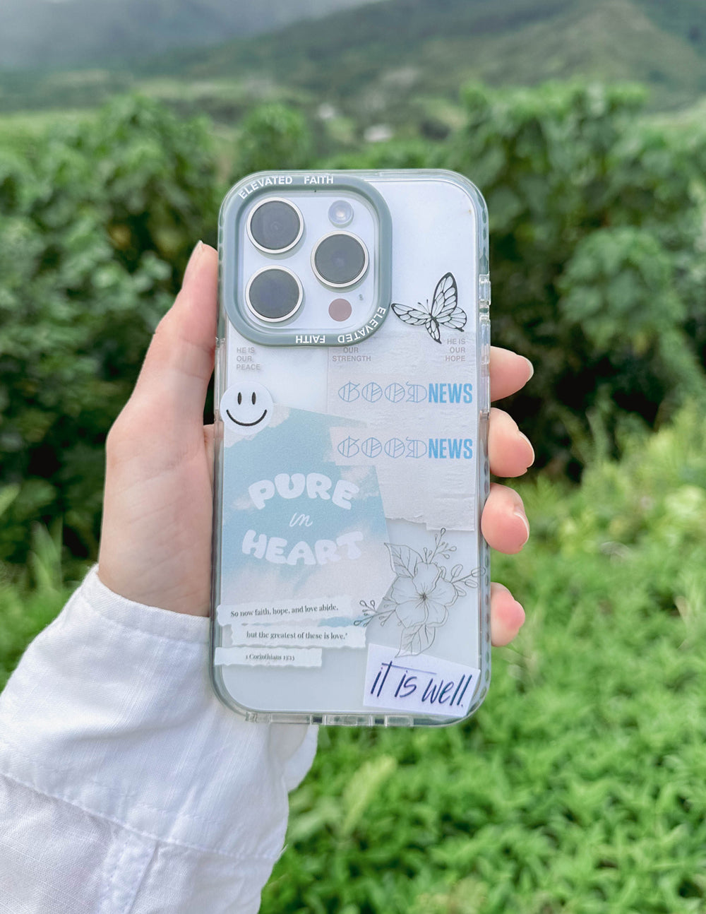 Person holding a phone with a clear case featuring text and graphics outdoors.