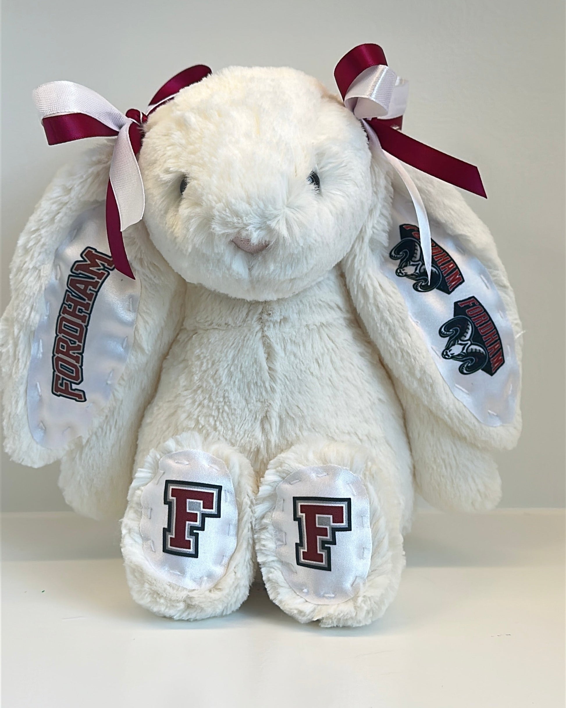 White stuffed animal with red and maroon accents and 'F' logos on a white background