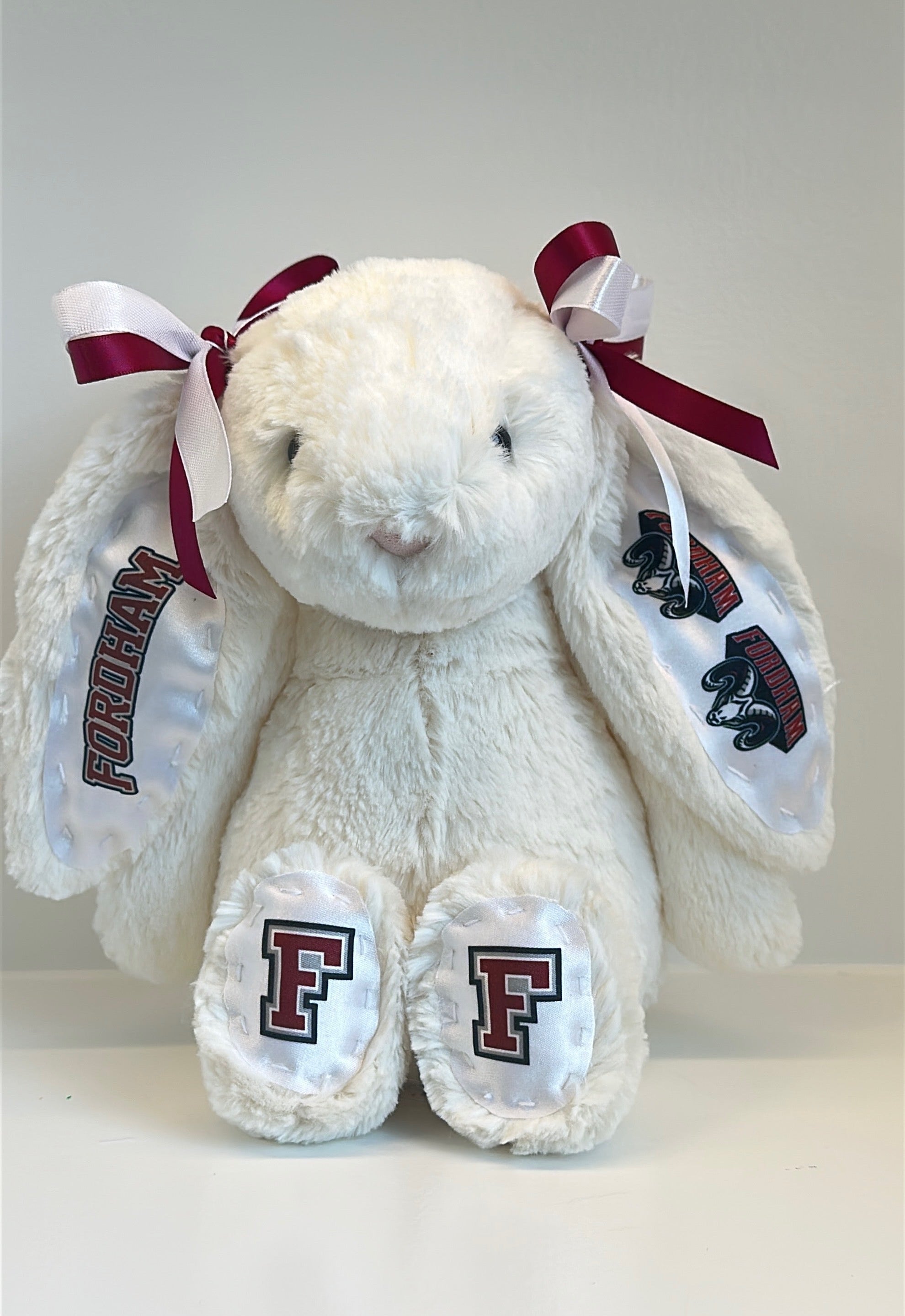 White stuffed bunny with red bows and 'F' logos on a white background