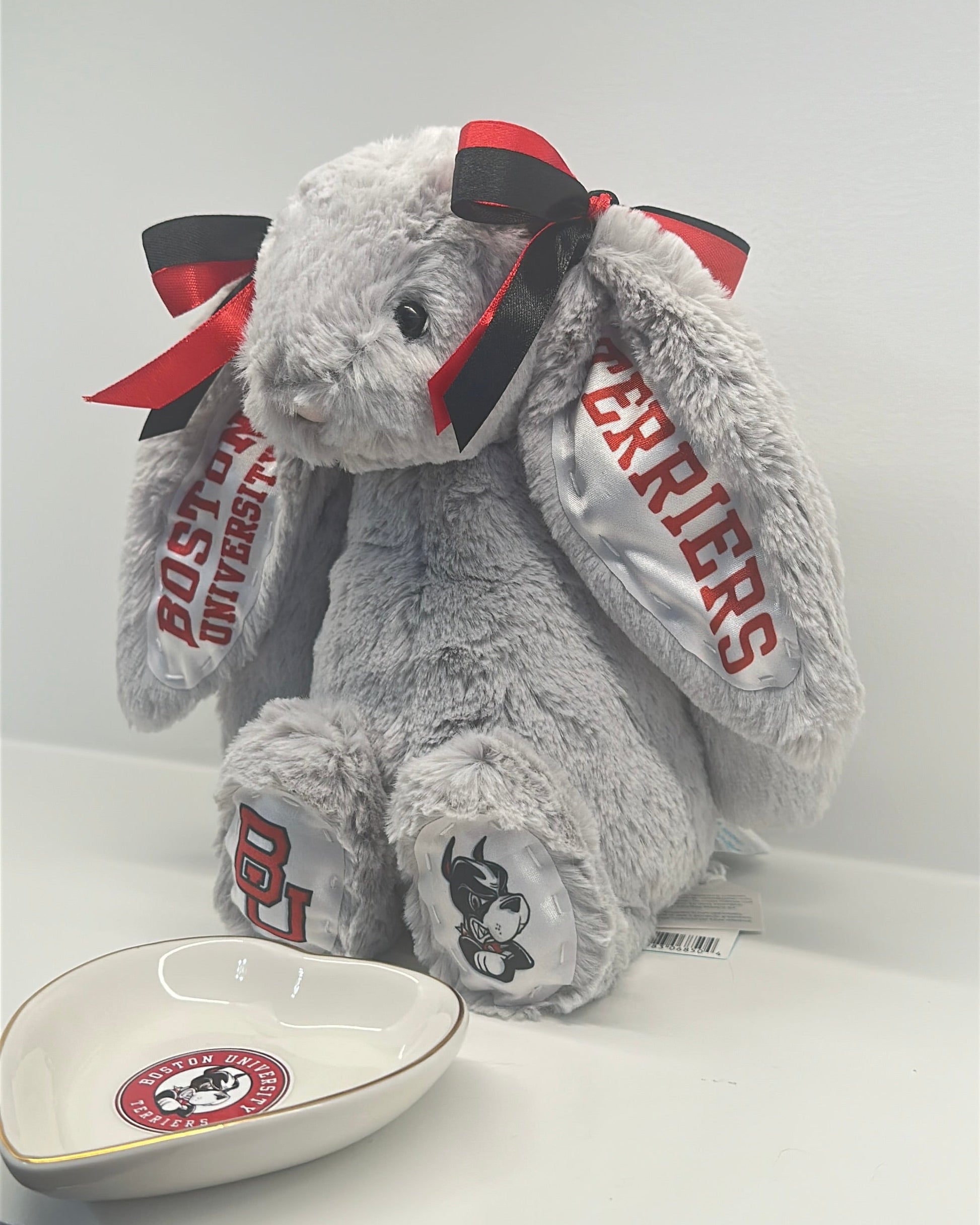 Gray plush bunny with red and black bow and 'Warriors' text on a white surface.