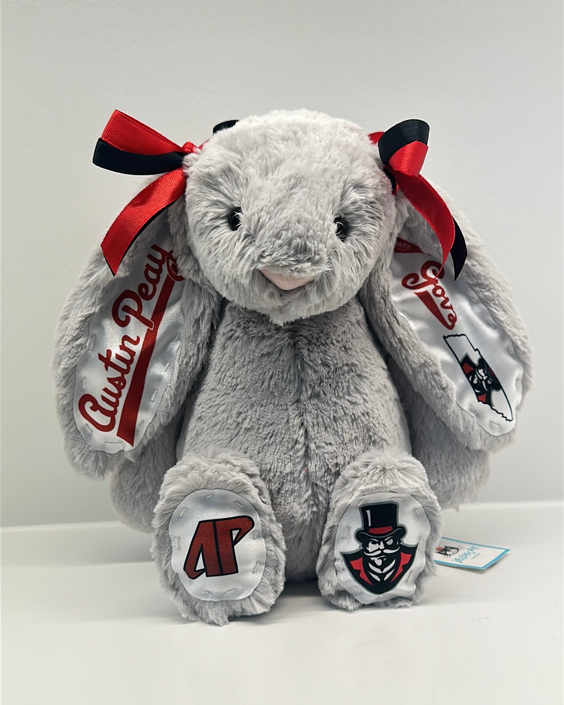 Gray plush bunny with red bows and 'Austin Peay' branding on a white background