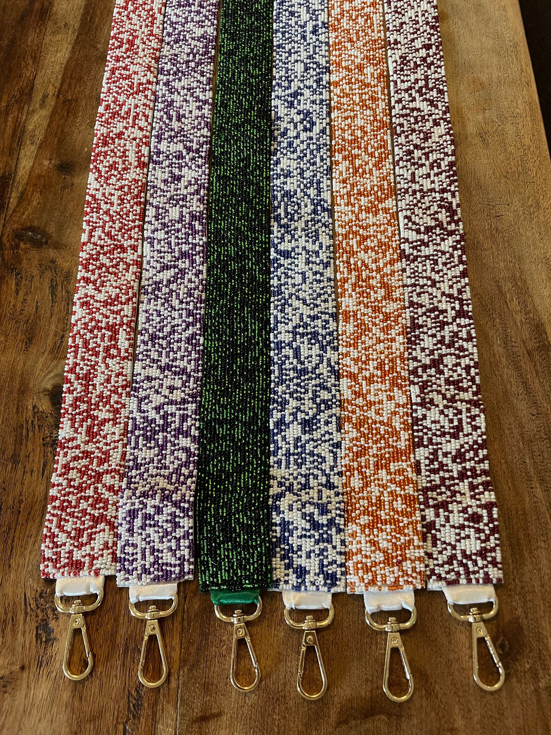 Set of colorful  beaded purse straps with metal hooks on a wooden surface