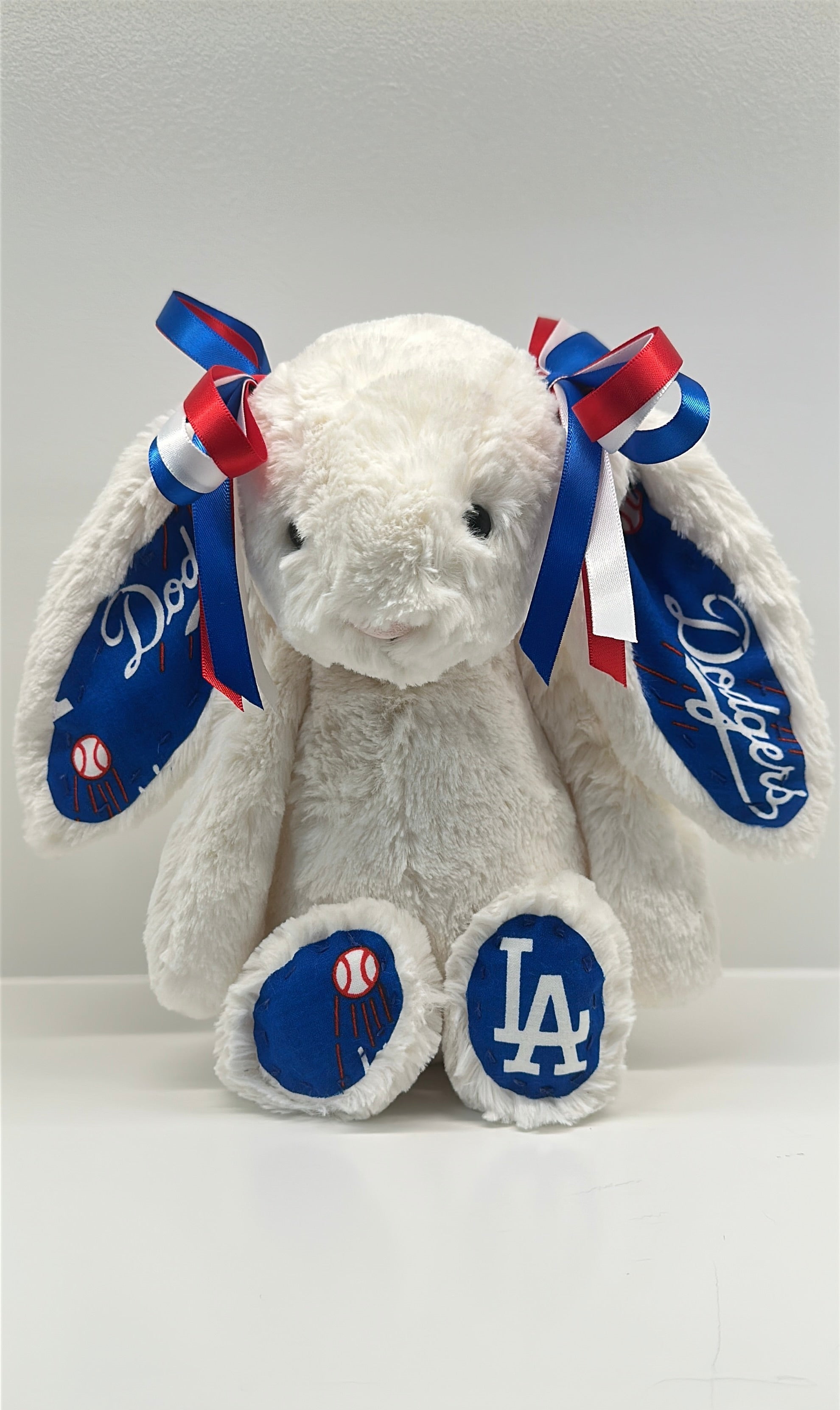 White plush bunny with blue and red bows and LA Dodgers logos on a white background