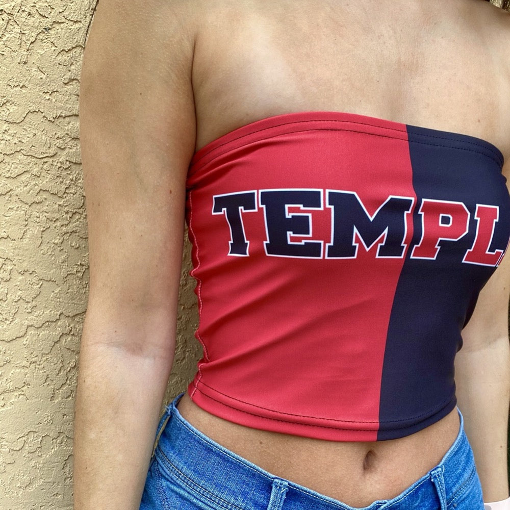 Person wearing a red and navy tube top with 'TEMPLE' printed on it against a beige wall.