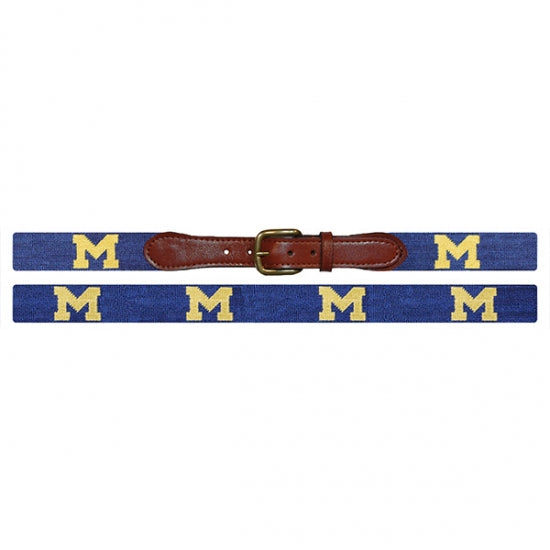 Navy belt with gold 'M' pattern and brown leather buckle on a white background