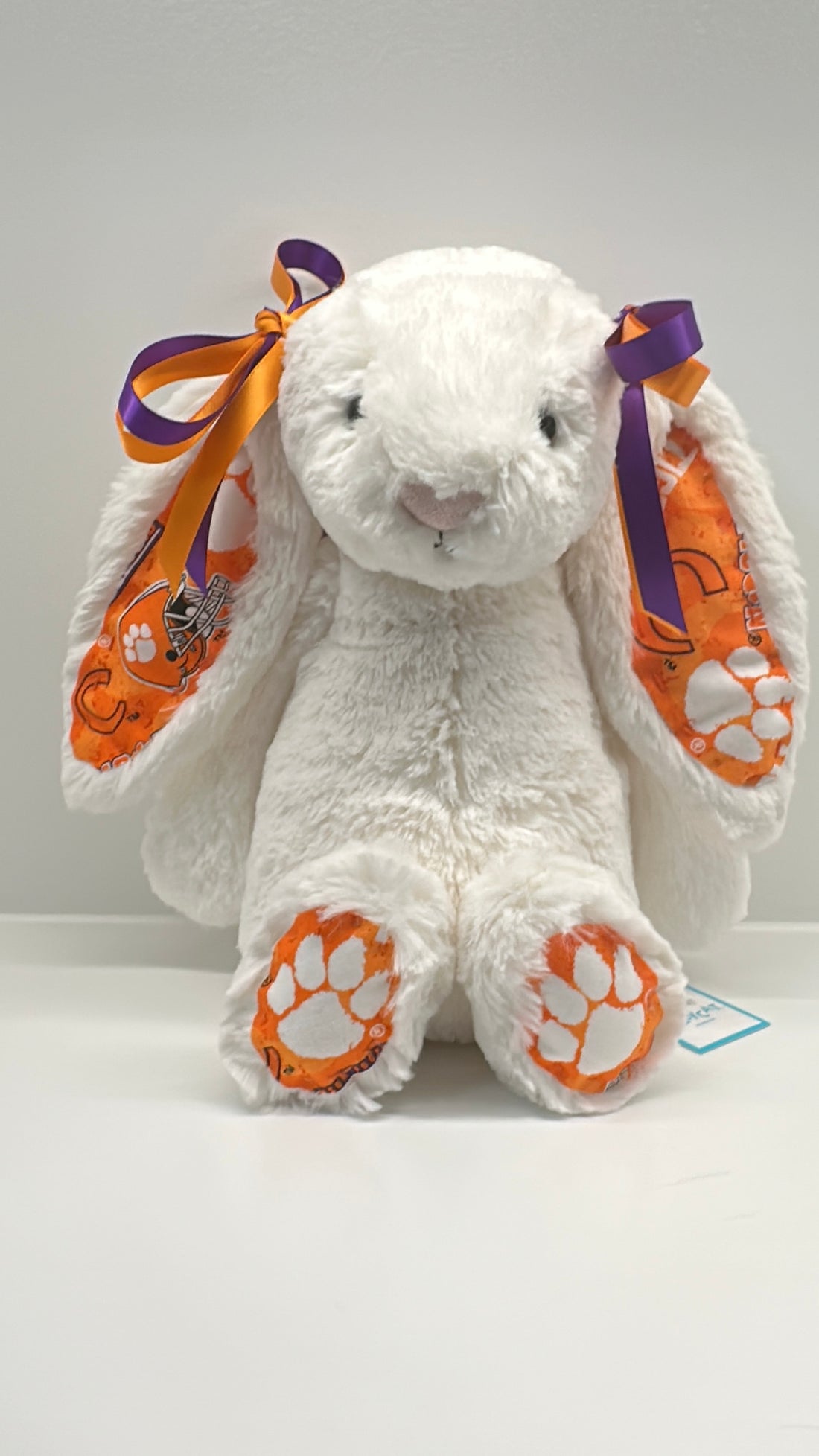 clemson White plush bunny with orange paw prints and a purple bow on a white background