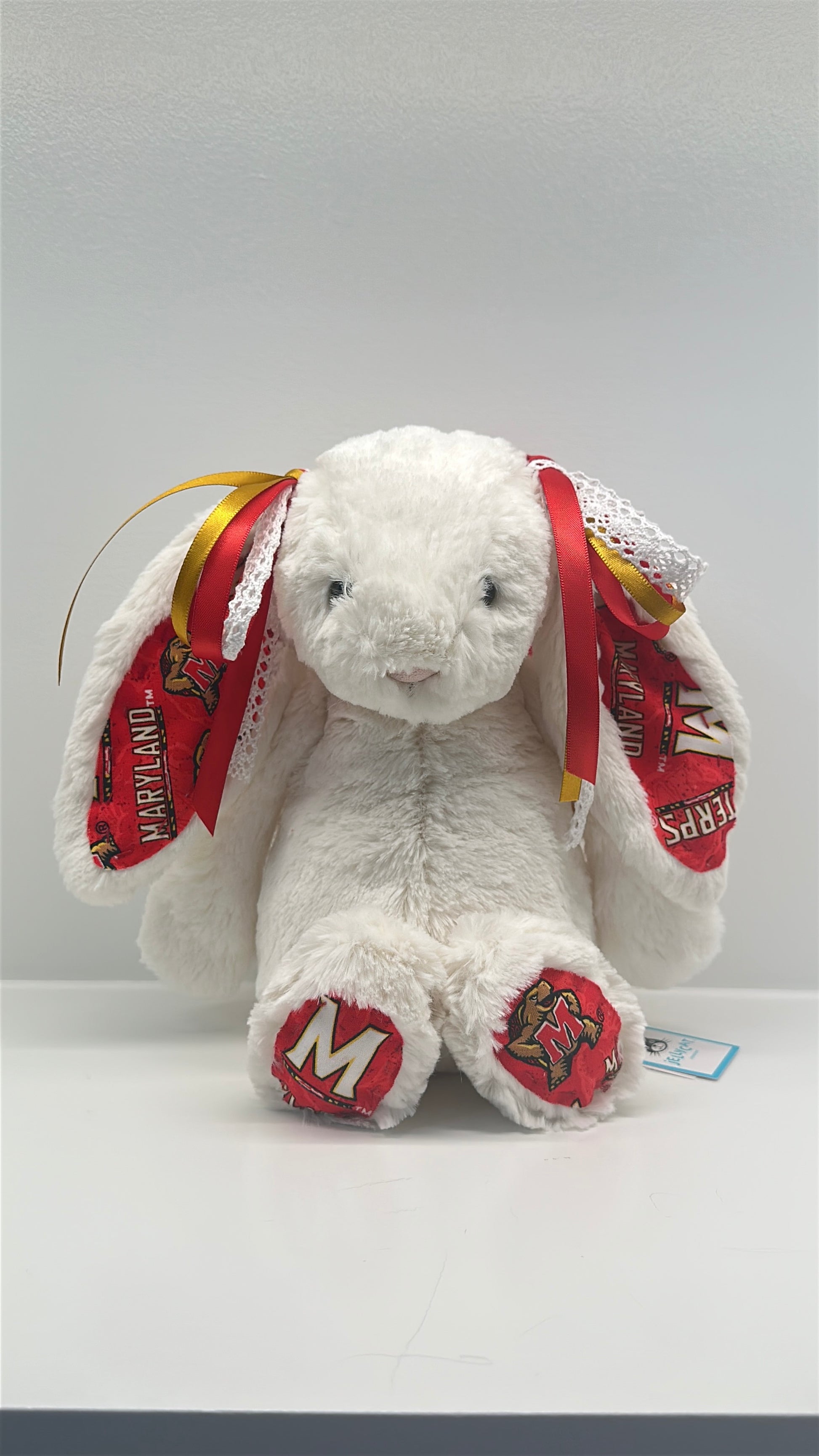 White plush bunny with red and yellow ears and paws on a white background