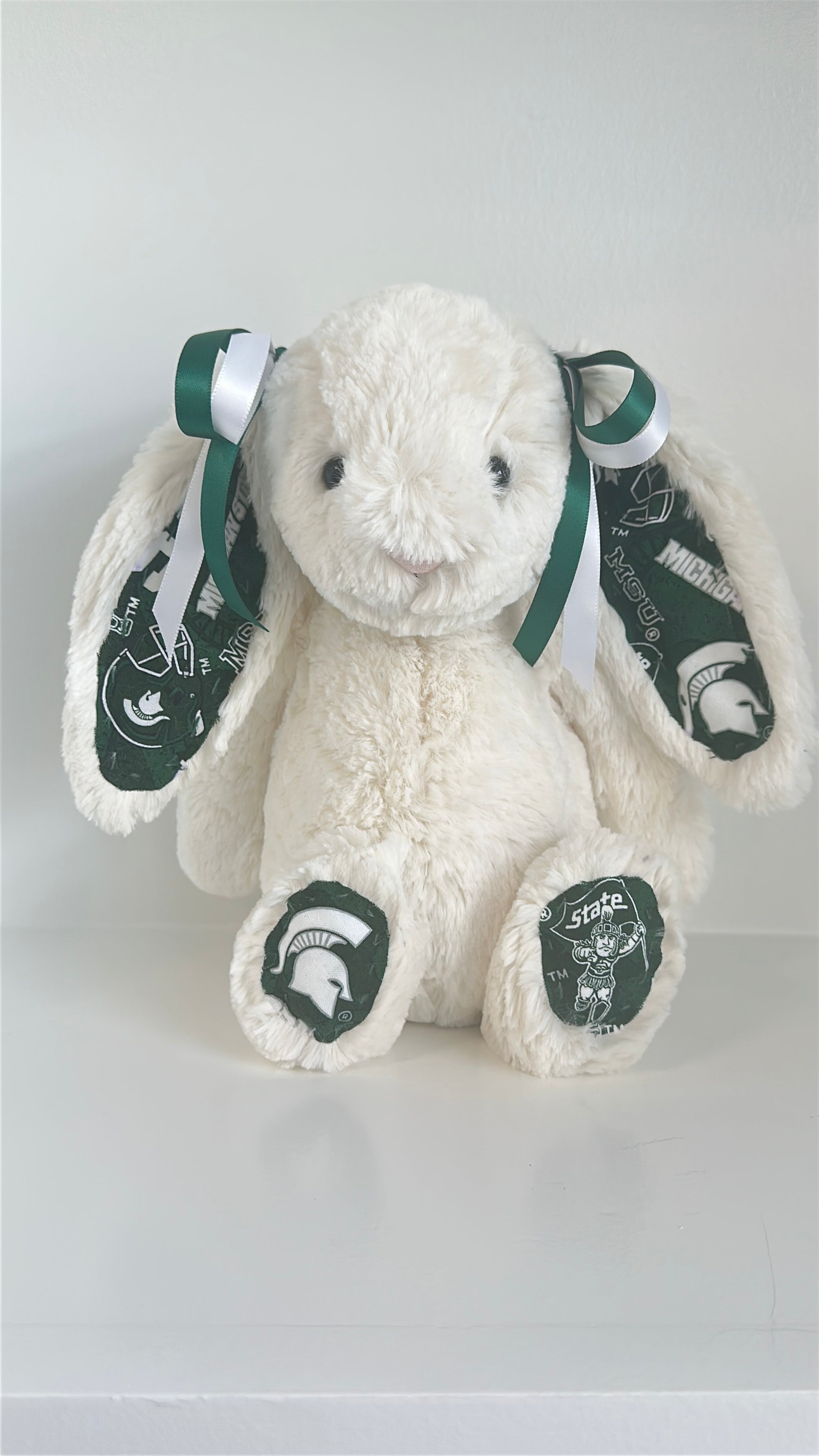 White plush bunny with green accents and Michigan State University logos on a light gray background