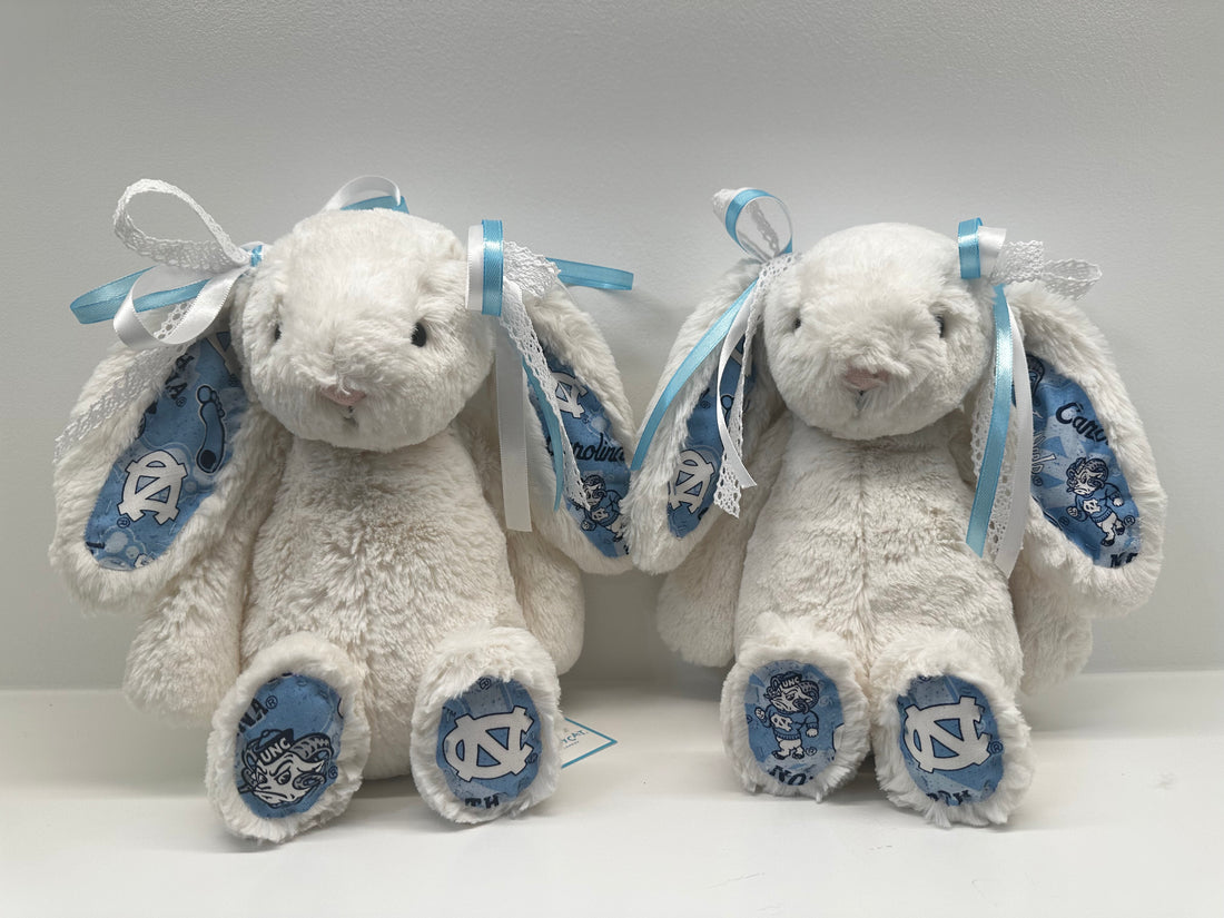 Gray plush bunny with blue ribbons and North Carolina logo on a white background