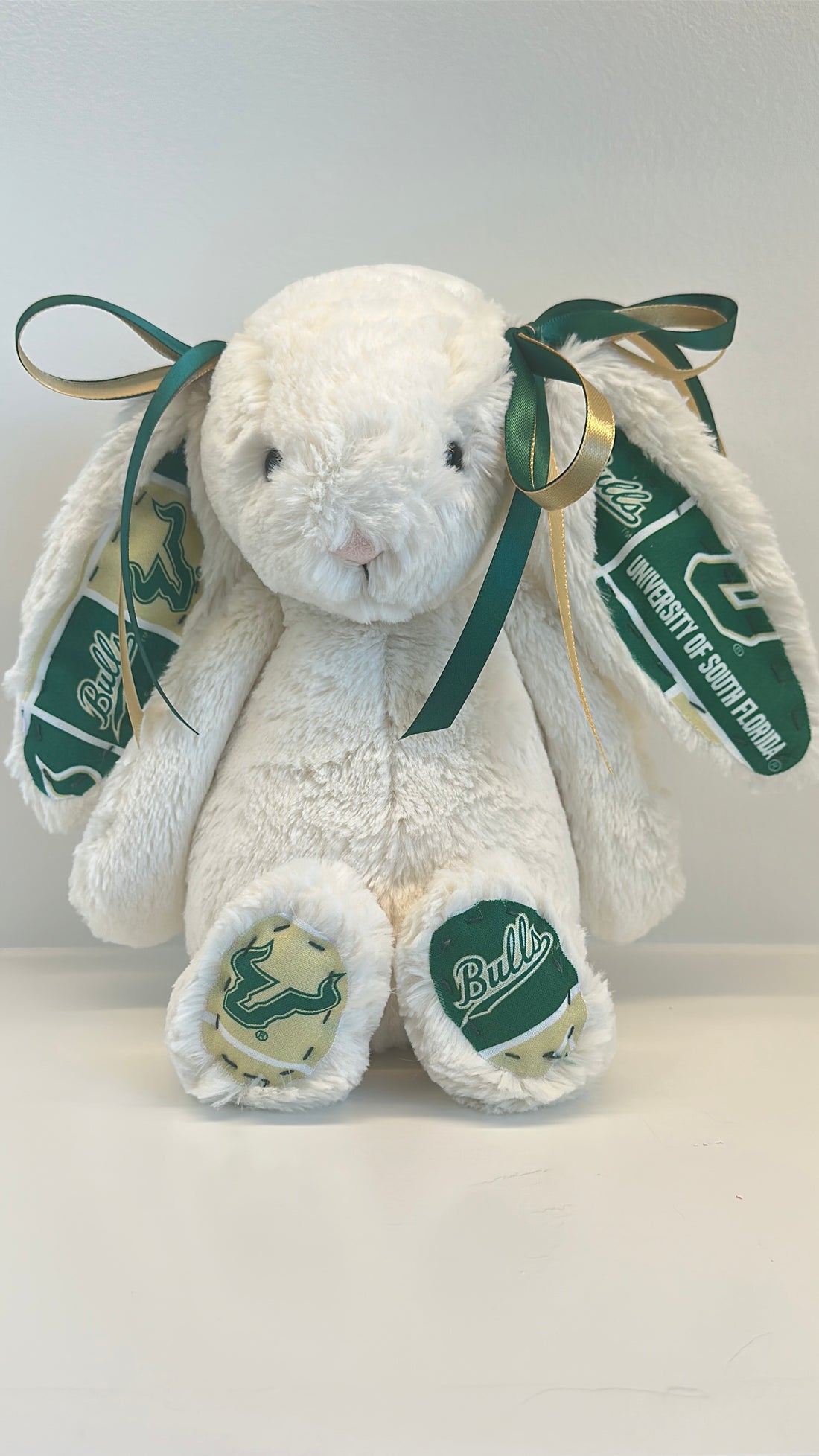 White plush bunny with green ribbons and logos on a white background