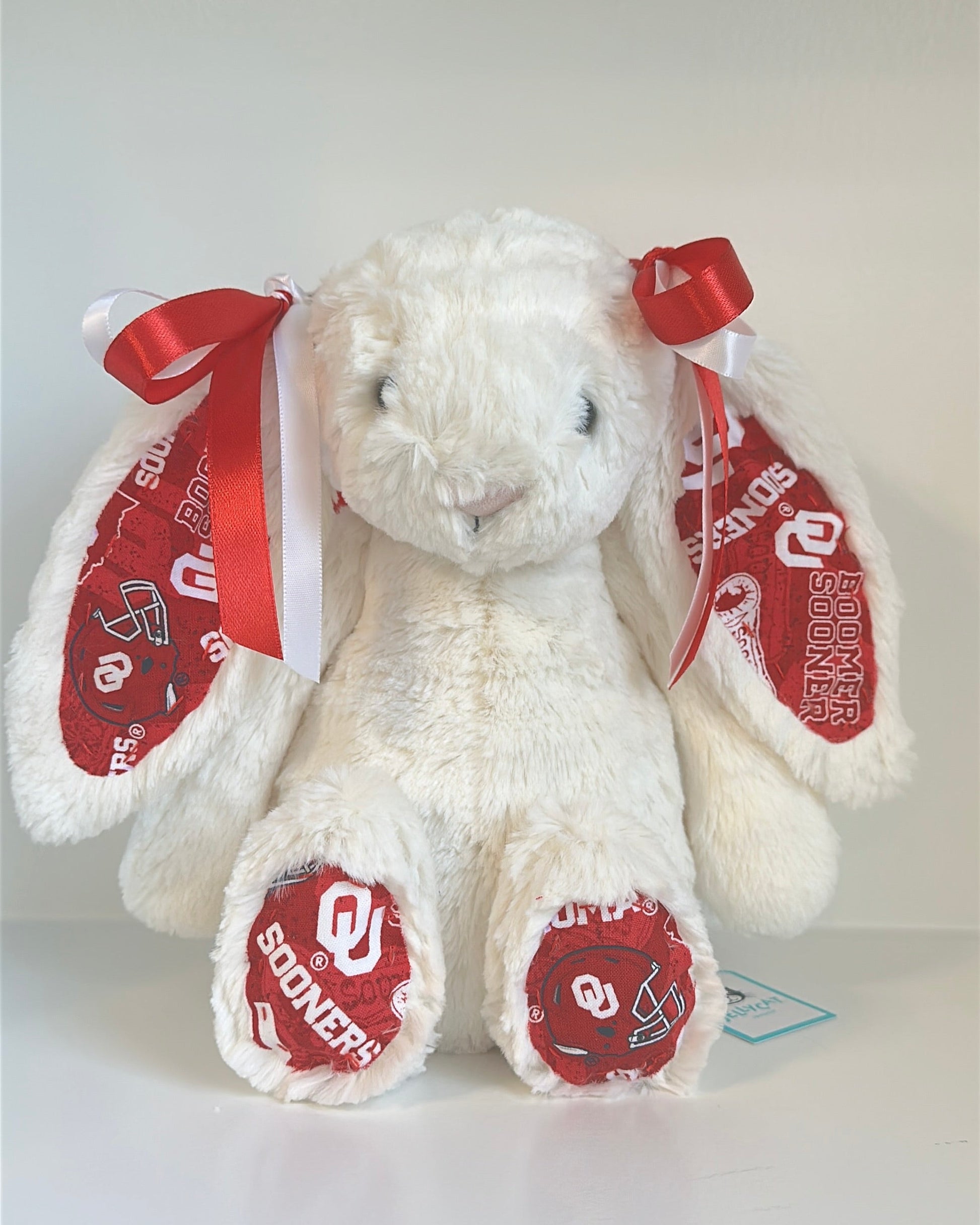 White stuffed bunny with red bows and 'OU' branding on a white background